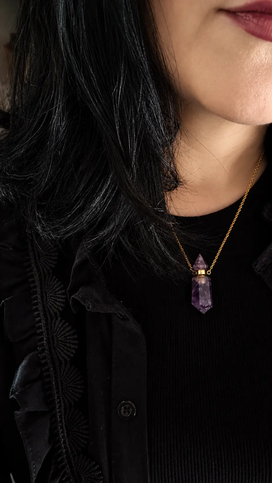 Collier amulette en améthyste violette et chaîne dorée, porté sur un chemisier noir