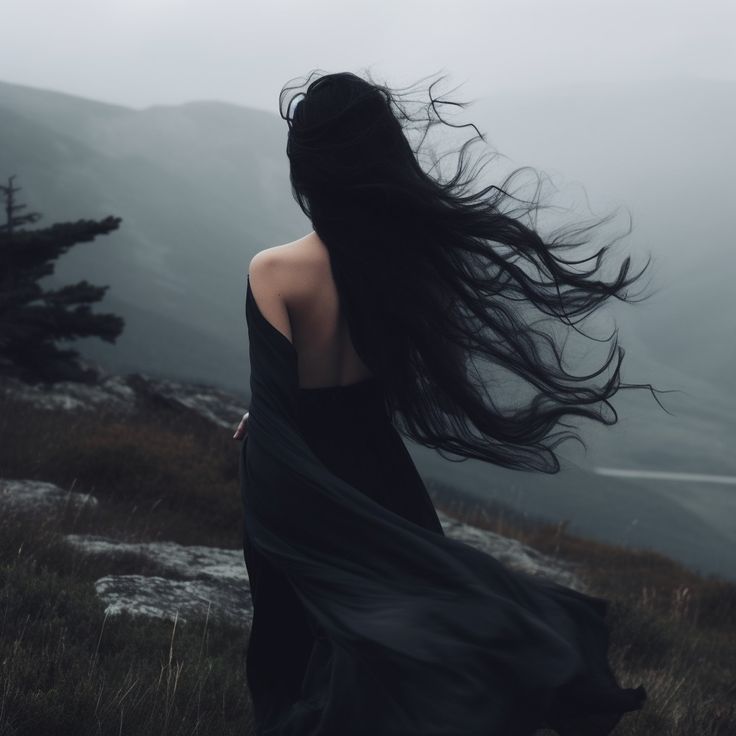 Femme de dos, longue chevelure au vent, sur une lande brumeuse