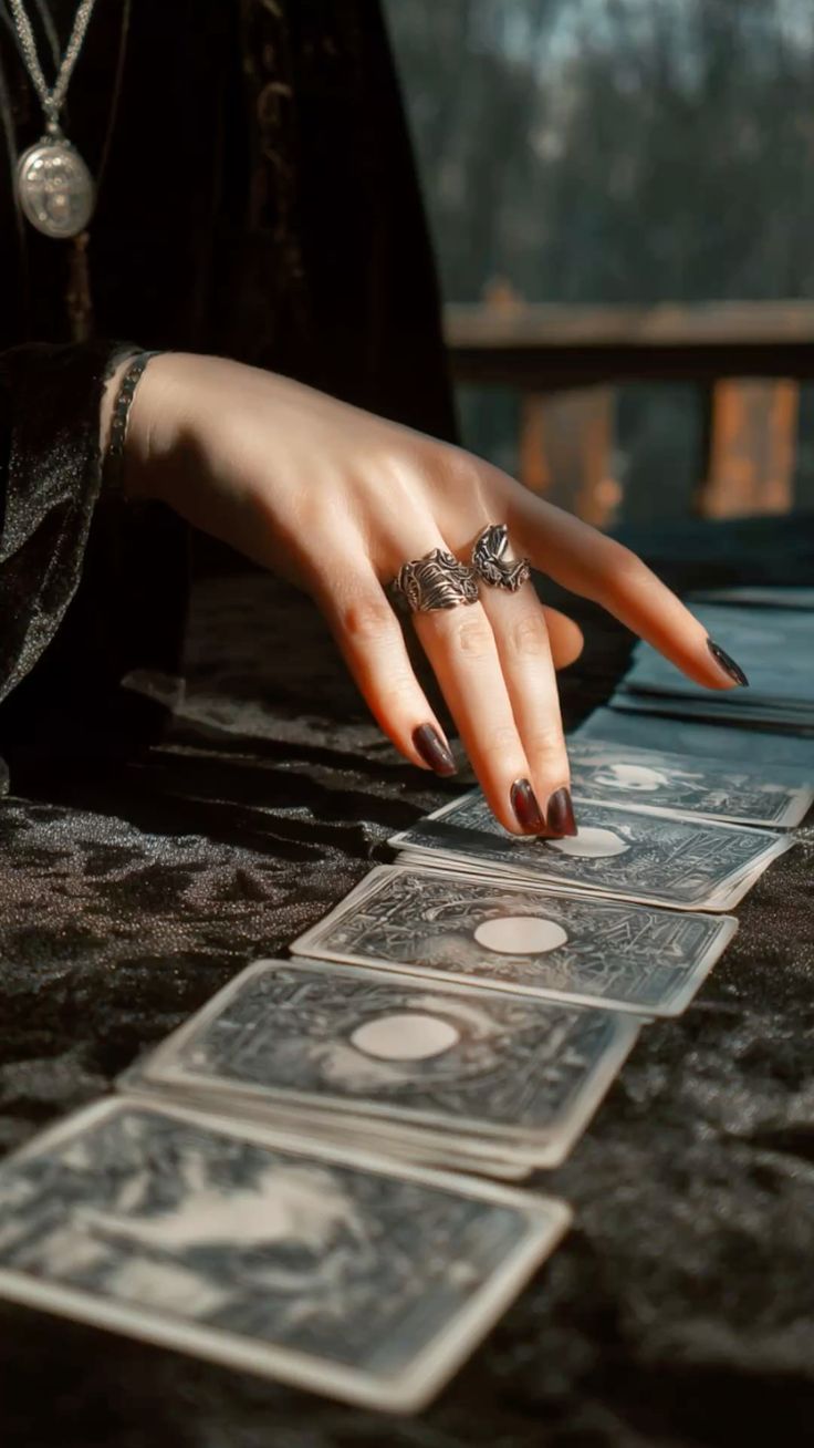 Main baguée déposant une rangée de cartes de tarot sur un velours sombre